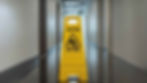 A wet floor sign in the middle of an office hallway.